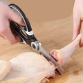 Tijeras de cocina Nova Home de acero inoxidable cortando pollo crudo sobre una tabla de madera