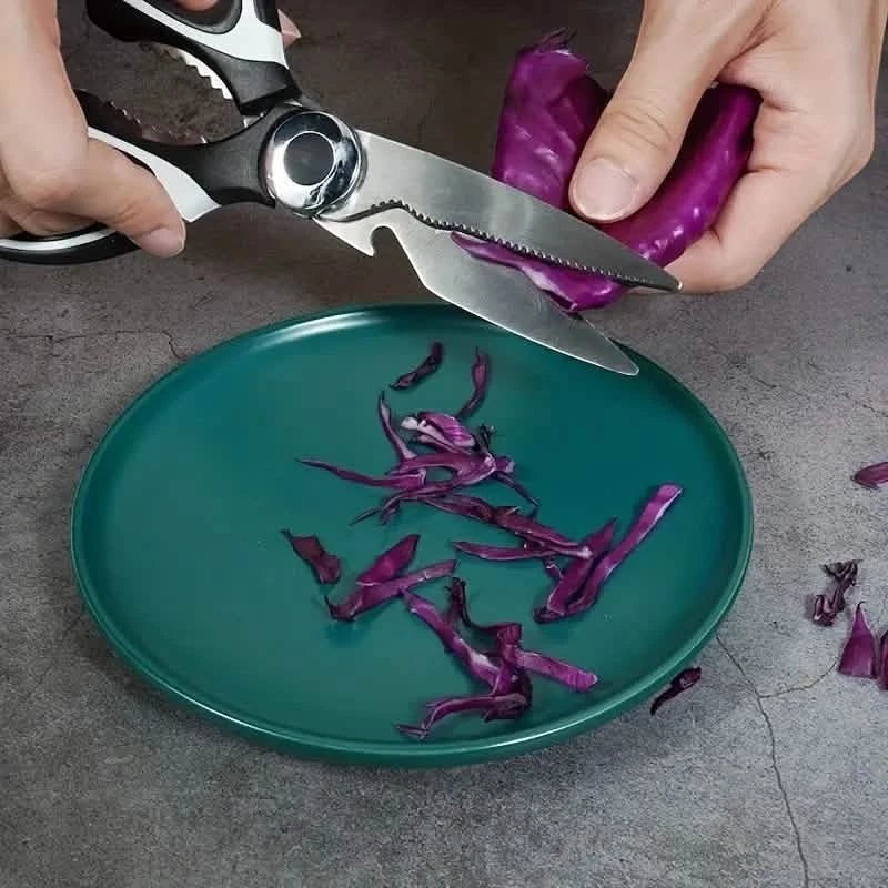 Tijeras de cocina Nova Home de acero inoxidable cortando col morada sobre un plato verde con mangos ergonómicos